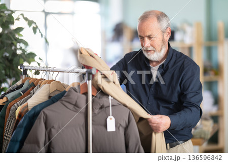 Family clothing store, senior man customer choose raincoat Family clothing store, senior man customer choose raincoat 136596842