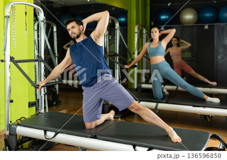Young man doing side leg lifts on professional pilates equipment Young man doing side leg lifts on professional pilates equipment 136596850