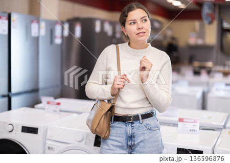 Young woman chooses washing machine or dishwasher Young woman chooses washing machine or dishwasher 136596876