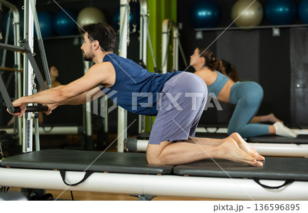 man is engaged in a group Pilates class and does abdominal exercises 136596895