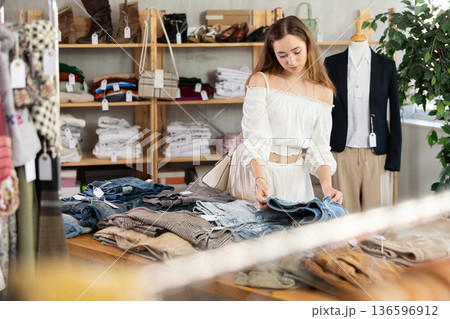 Selective young woman choosing pantaloons in clothing store Selective young woman choosing pantaloons in clothing store 136596912