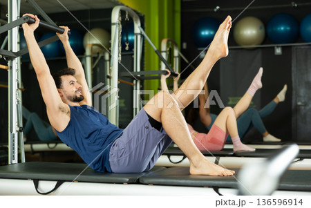 man is engaged in a group Pilates class and does abdominal exercises man is engaged in a group Pilates class and does abdominal exercises 136596914