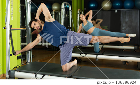man is engaged in a group Pilates class and does abdominal exercises 136596924