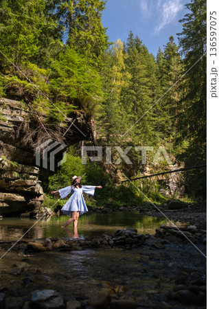 Woman Strolling by River in Forest 136597075