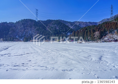 美山かやぶきの里で見た冬の日本の田舎風景、雪に覆われた田んぼと山々、澄み渡る青空 美山かやぶきの里で見た冬の日本の田舎風景、雪に覆われた田んぼと山々、澄み渡る青空 136598143
