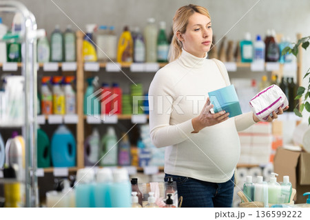 Thoughtful pregnant customer choosing feminine pads in hygiene store Thoughtful pregnant customer choosing feminine pads in hygiene store 136599222