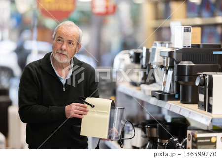 Elderly man choosing a coffee machine for his kitchen Elderly man choosing a coffee machine for his kitchen 136599270