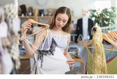Woman trying on beige top in clothing store Woman trying on beige top in clothing store 136599281