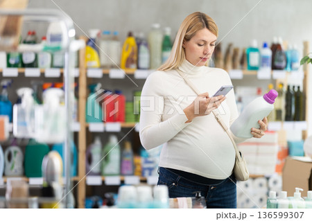 Pregnant woman scanning detergent barcode, checking ingredients Pregnant woman scanning detergent barcode, checking ingredients 136599307