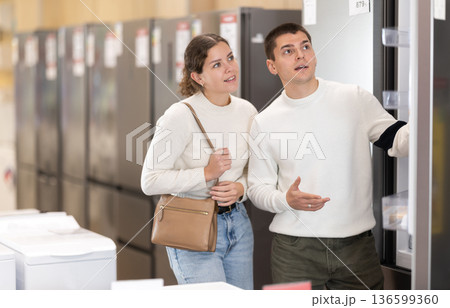Girl with help of guy sales consultant choosing fridge 136599360