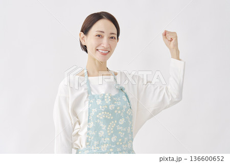 エプロンをつけた女性 やる気のジェスチャー 白背景 エプロンをつけた女性 やる気のジェスチャー 白背景 136600652