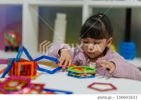 preschool child girl building structures with magnetic construction tiles. geometric shapes preschool child girl building structures with magnetic construction tiles. geometric shapes 136601631