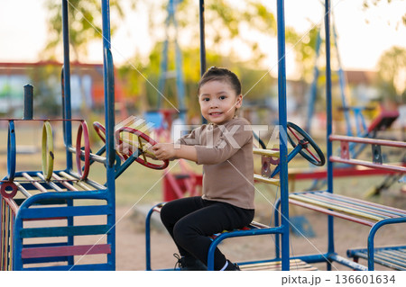 child girl playing with a steering wheel toy on playground 136601634