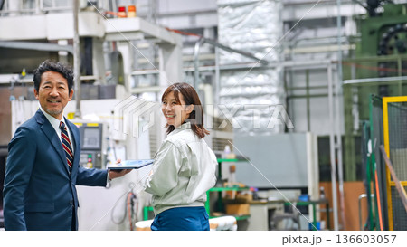 工場で会話する男性ビジネスパーソンと女性作業員 136603057