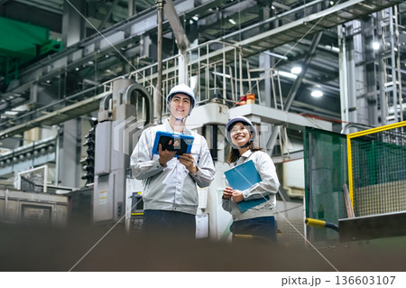 タブレットを持って工場機械を点検する男女作業員 136603107