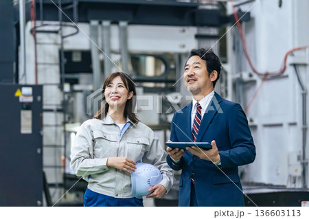 工場を視察する男性ビジネスパーソンと女性作業員 工場を視察する男性ビジネスパーソンと女性作業員 136603113