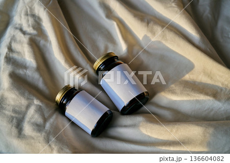 Two amber glass bottles with blank labels on fabric Two amber glass bottles with blank labels on fabric 136604082