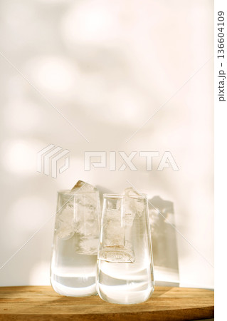 Drinking glasses with ice water and sunlight shadows 136604109