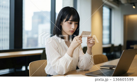 オフィスのデスクで名刺を真剣に確認する日本人ビジネスウーマン 136605599