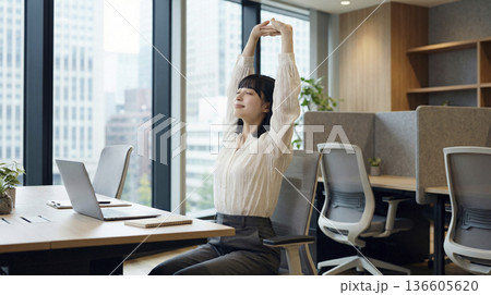 オフィスのデスクで背伸びをしてリフレッシュする日本人女性 136605620