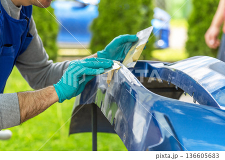 Repairing car body by puttying close up work after the accident by working sanding primer before painting. 136605683