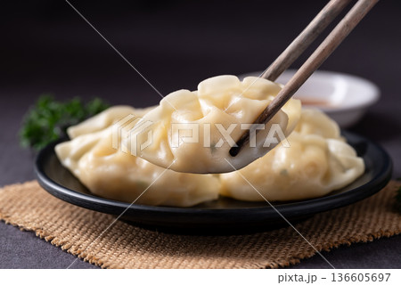 Close up of delicious steamed dumplings with chopsticks and sesame oil dipping sauce 136605697