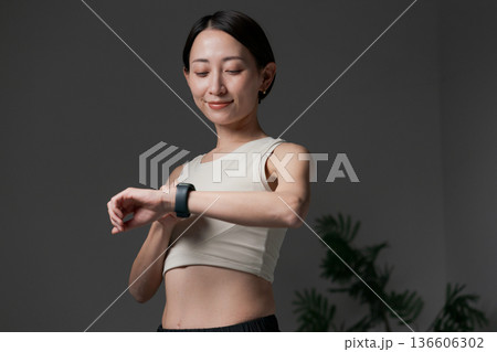 スマートウォッチを見る筋トレする女性 スマートウォッチを見る筋トレする女性 136606302