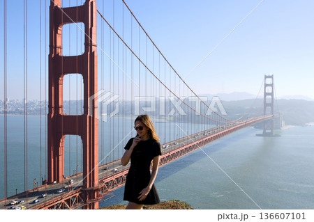 Woman standing near Golden Gate Bridge in black dress 136607101