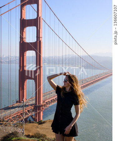 Stylish woman in black dress posing near Golden Gate Bridge 136607107