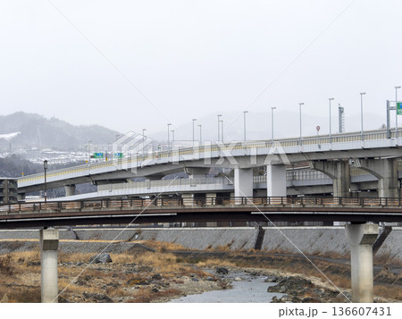 雪が降る山と川沿いの景色 136607431