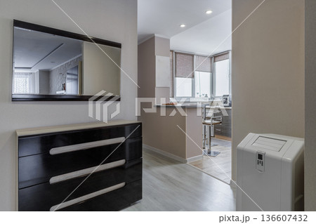 Modern Hallway Interior with Dark Commode Mirror and Kitchen View Modern Hallway Interior with Dark Commode Mirror and Kitchen View 136607432