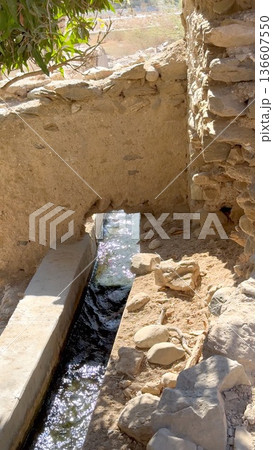 Rural Farmer Maintains Ancient Water Delivery Under Bright Sunlight. Resilient Rural Irrigation Setup With Farmer Tending To Classic Water Flow System In Sunlight 136607550