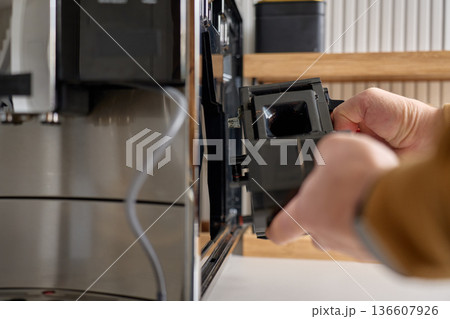 Person taking out internal brew group unit from modern automatic coffee machine. Concept of appliance maintenance, cleaning and home coffee preparation Person taking out internal brew group unit from modern automatic coffee machine. Concept of appliance maintenance, cleaning and home coffee preparation 136607926