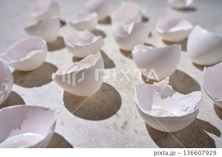 Empty white eggshell halves scattered on light marble surface. Broken chicken eggs on kitchen countertop. Concept of food waste, cooking preparation and biodegradable kitchen leftovers 136607929
