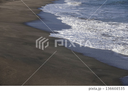 夕陽に照らされた波打ち際の砂浜とさざ波 136608535