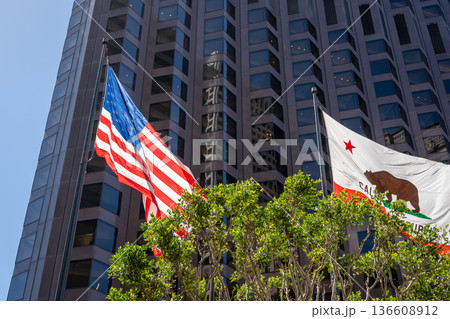 American and California flags waving in front of a modern building 136608912
