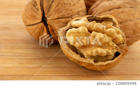 Walnut kernels and whole walnuts on wooden table 136609394