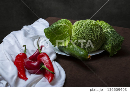 Still life with Savoy cabbage, vegetables and fruits on a white tablecloth 136609498