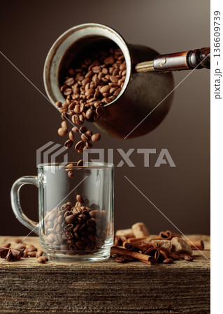 Roasted coffee beans is poured in a clear glass mug. Roasted coffee beans is poured in a clear glass mug. 136609739