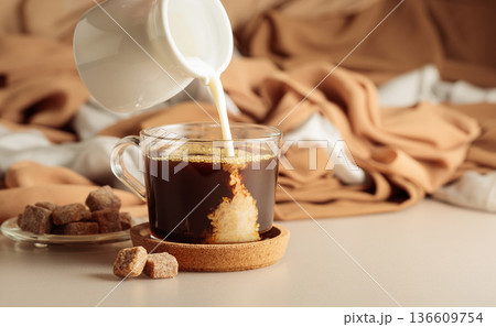 Pouring cream in black coffee. 136609754