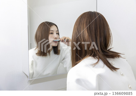 鏡を見て歯磨きする女性 鏡を見て歯磨きする女性 136609885