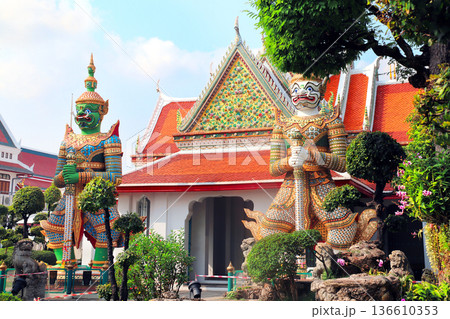 Two Colorful Giant Yaksha statues, guarding the entrance of Buddhist Temple of Dawn Wat Arun, sightseeing landmark of Bangkok, Thailand. Topic of summer vacation, relaxing, travel, trip, cruises, tour Two Colorful Giant Yaksha statues, guarding the entrance of Buddhist Temple of Dawn Wat Arun, sightseeing landmark of Bangkok, Thailand. Topic of summer vacation, relaxing, travel, trip, cruises, tour 136610353