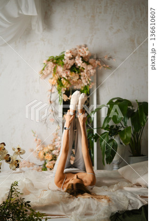 Woman practicing yoga poses in a bright room filled with plants and flowers Woman practicing yoga poses in a bright room filled with plants and flowers 136610607