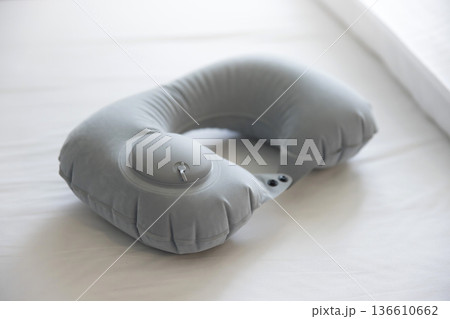 ホテルのベッドの上に置かれたエアポンプ式ネックピロー 136610662