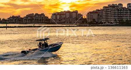 Yacht go to sunset marina. Boating and yachting. Luxury lifestyle. Yacht at Fisher island luxury residential building. Summer vacation. Fisher island sunset. Luxury motor boat yacht. Copy space 136611163