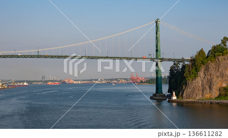 Vancouver, Canada - May 29, 2019: View of Lions Gate Bridge from Stanley Park. Bridge architecture with landmark view and Canada flag on the hill. Travel concept. Lions Gate Bridge. Vancouver BC 136611282