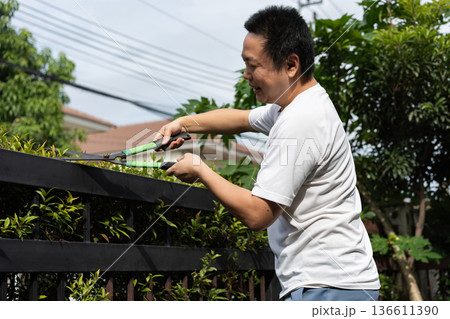 A man takes care of his home by cleaning the floor and trimming the garden. Simple daily routines that reflect pride in a clean and pleasant home. 136611390
