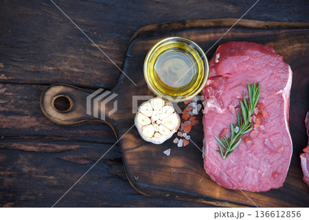 Top view raw beef tender meat steak grill pork barbeque on wooden board. Steak western cuisine ingredient fresh herb meat pepper olive oil garlic chilli tomato salt rosemary on wood plate outdoor. Top view raw beef tender meat steak grill pork barbeque on wooden board. Steak western cuisine ingredient fresh herb meat pepper olive oil garlic chilli tomato salt rosemary on wood plate outdoor. 136612856