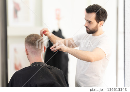 Professional barber cutting male client's hair at salon Professional barber cutting male client's hair at salon 136613348