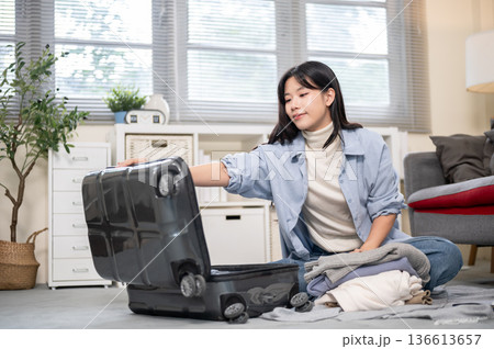 Asian woman opening her luggage organize or packing while sitting on bedroom or living room's floor Asian woman opening her luggage organize or packing while sitting on bedroom or living room's floor 136613657